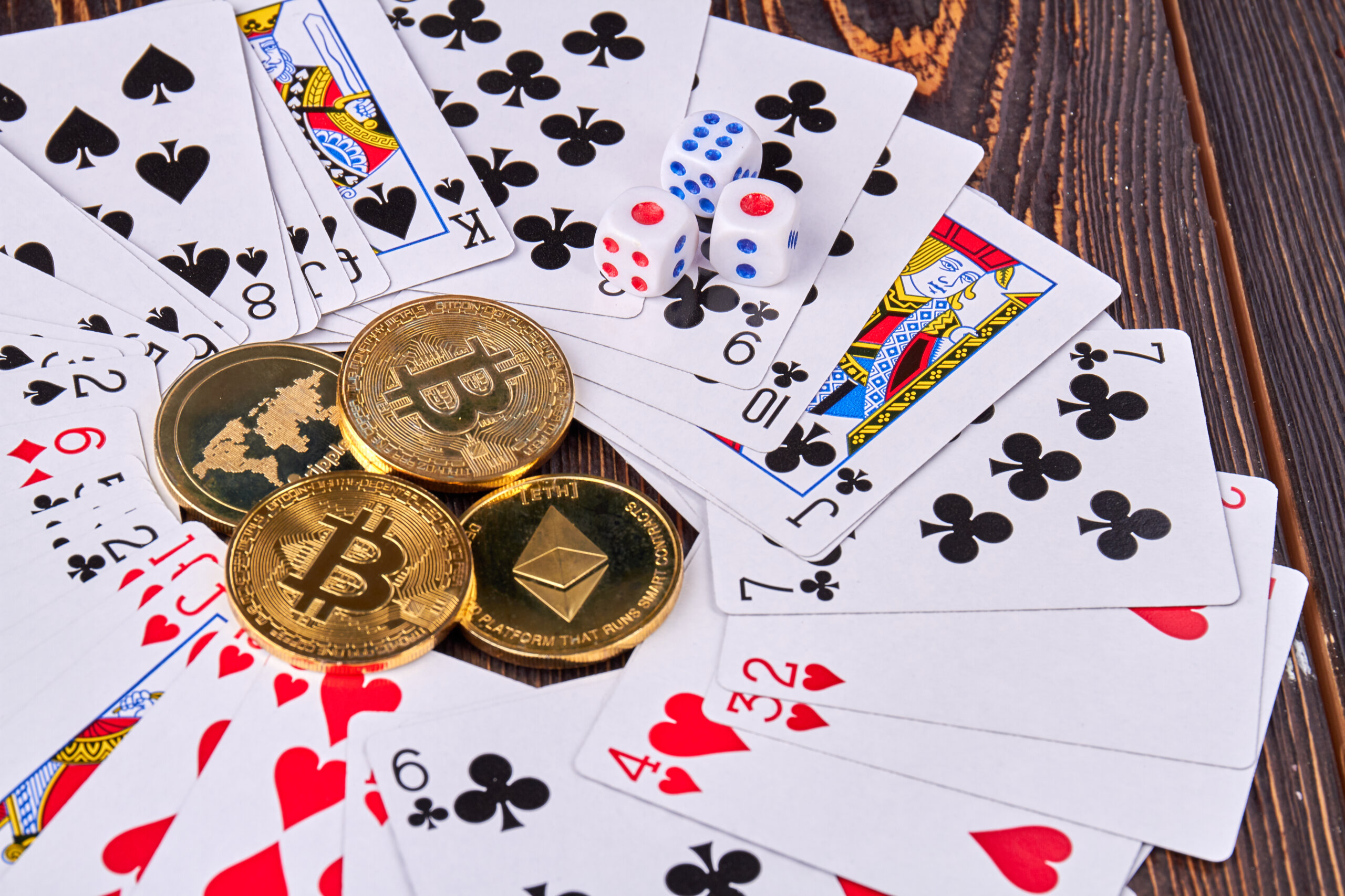 Close-up bitcoins with cards and dices on wooden desk.